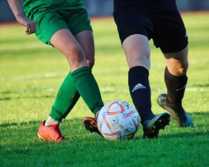 cropped image of two people playing football on a grass pitch: image showing how gait analysis can benefit footballers in Helensburgh