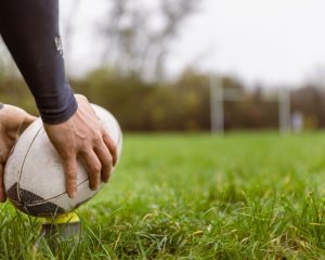 cropped image of a man's hands holding a rugby ball preparing to kick: image showing how gait analysis can benefit rugby players in Helensburgh