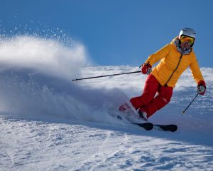 downhill skier wearing yellow jacket and red trousers: image showing how gait analysis can benefit skiers in Helensburgh