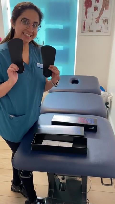 Physiotherapist Sakshi Duseja holding Phits custom orthoses beside a treatment table in a treatment room at The Lomond Clinic, Helensburgh