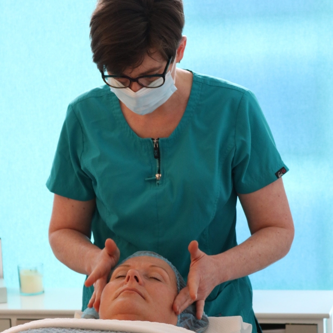 Skin specialist and beauty therapist jill du Toit, part of the integrated whole-person healthcare team at The Lomond Clinic, massages the skin of a female client lying on a treatment bed.