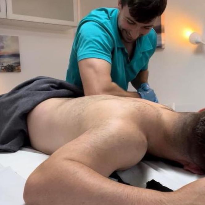 Craig Macdonald sports and massage therapist, part of the integrated whole-person healthcare team at The Lomond Clinic, massages the back of a male patient lying on a treatment bed.