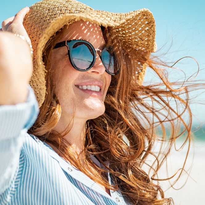 Smiling woman wearing sunglasses and sun hat for sun safety