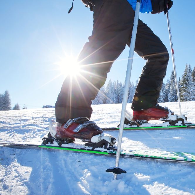 Cropped image of a skier's egs and feet with sun in the background
