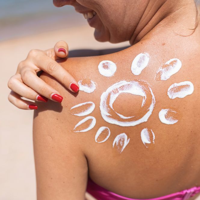 Smiling woman applying sunscreen in a sun pattern on her back