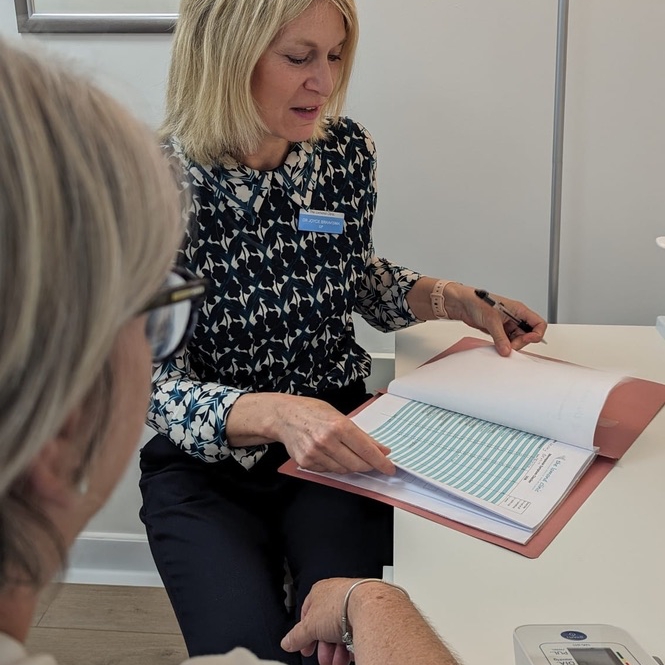 GP Dr Joyce Braaksma consults with a female patient, reading patients notes, showing private healthcare services helensburgh