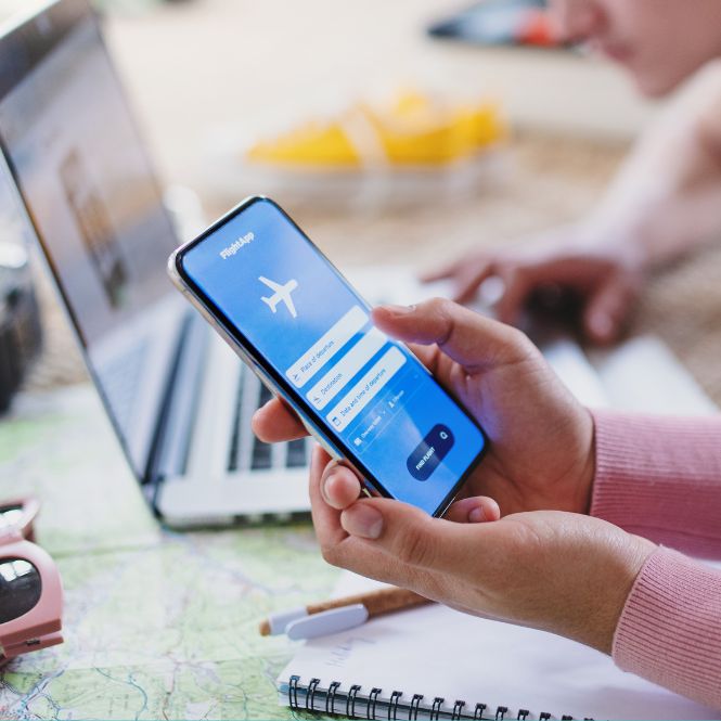 Planning for travel: young couple look at flight booking app on mobile and on laptop