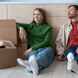 Young woman moving house with her male partner, sitting on floor surrounded by boxes